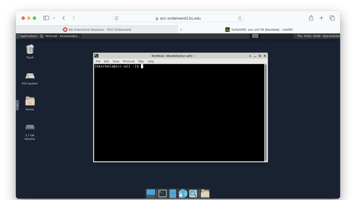 A Linux desktop running inside a browser tab. A thin bar runs across the top with an Applications menu on the left, a list of open windows next to it, a workspace switcher on the right, and the clock and user name at the far right. Icons for Trash, File System, Home and a disk volume run down the left edge. A terminal window sits in the middle of the screen, and a row of application shortcuts sits at the bottom center.